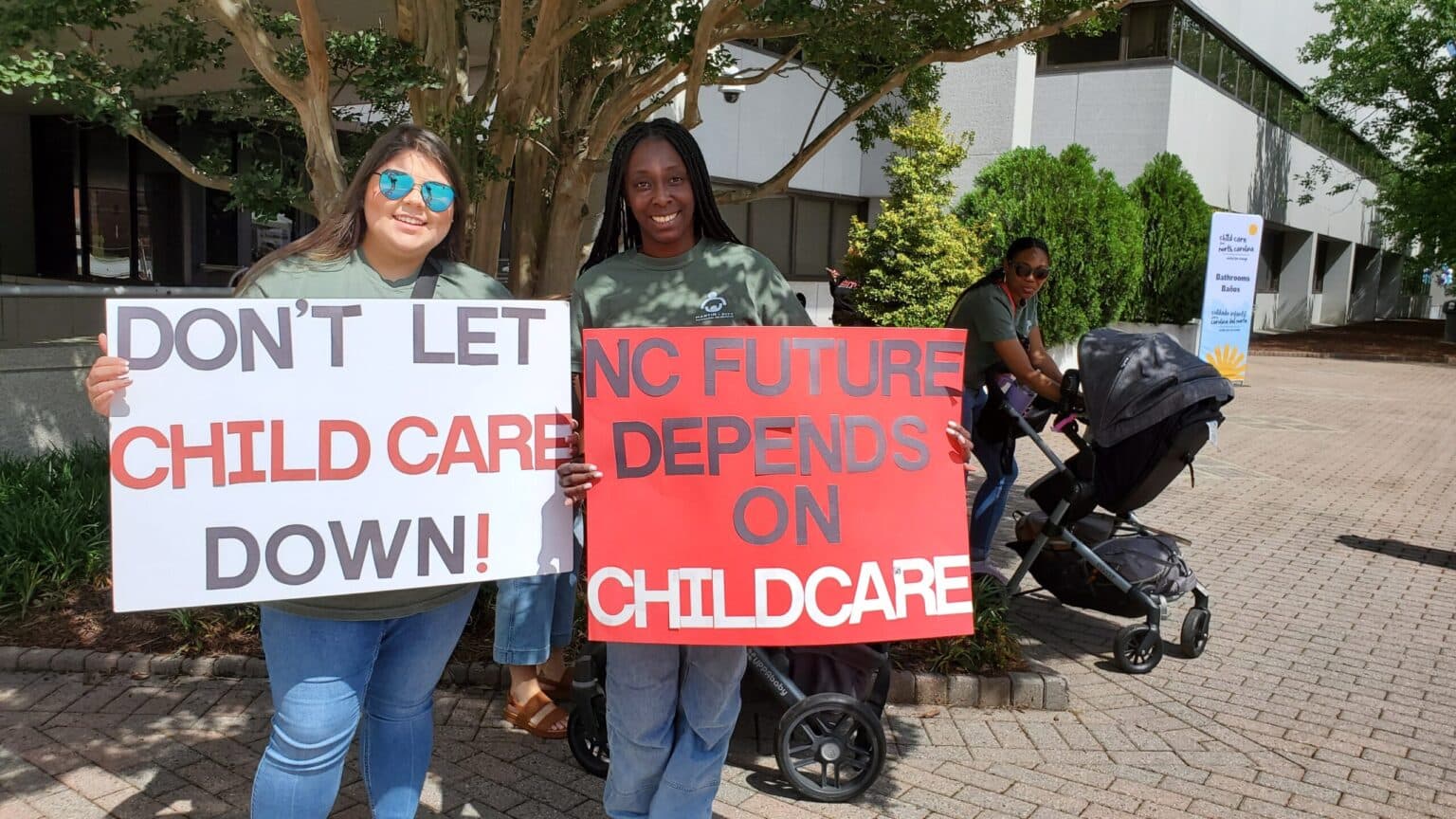 Childcare workers hold signs calling for legislative funding.