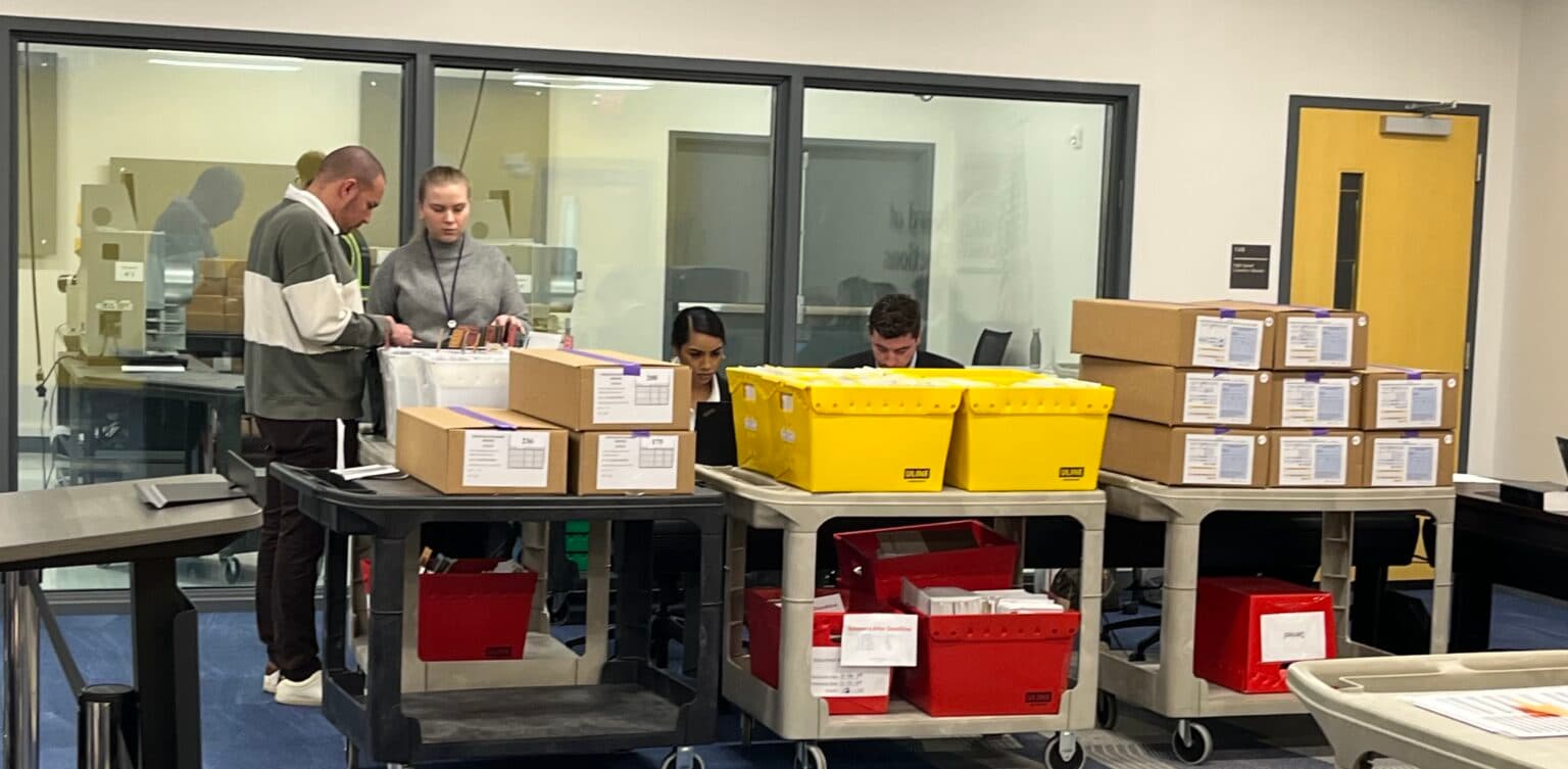 Bins of absentee ballots await review at the Wake County Board of Elections in November 2024.