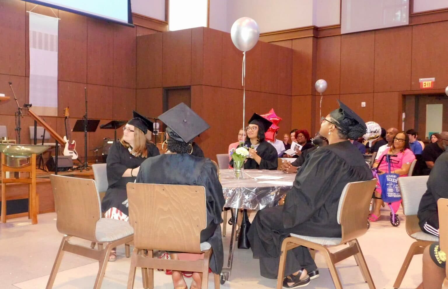 StepUp participants gather at tables during a graduation ceremony.
